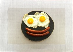 Top view of fried egg and sausage smile face on black plate in white table, breakfast serve for kid, funny breakfast. High quality photo