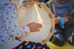 The child beats the tambourine. A child learning to play musical instruments.