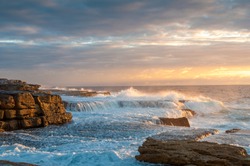 Ocean coastline scene with waves crushing over rocks at sunrise. Sunset, sunrise seascape nature background 