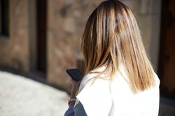 Anonymous girl on her back using smartphone while walking around town