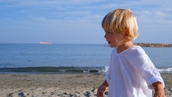 little boy in a white shirt by the sea
