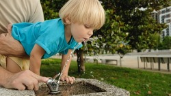Cute little boy face portrait drink water in a park from drinking fountain slow motion
