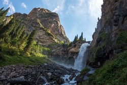 Beautiful waterfall in mountains with. Barskoon waterfall - splashes of Champaign. Travel, tourism in Kyrgyzstan concept. Scenic background. Natural background. Outdoor landscape. 