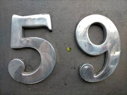 Number fifty-nine,59 in chrome colored metal.Number placed on dark colored concrete.