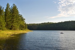 Photograph of the sunny side of a remote northwoods lake in Wisconsin in early evening as the sun dips low in the sky.