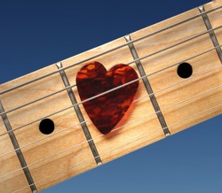 Guitar with heart-shaped pick. Closeup of fretboard.