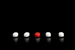Five pills in red and white on a black background.