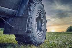 An off-road car splattered with mud against a beautiful sky. Car tire and mudguard 4x4. Off-road tire