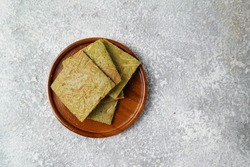 Close up and selective focus of Macha Tea Crackers with cheese in a wooden plate on a white background. The perfect blend for tea time. Grainy noise from the crackers texture