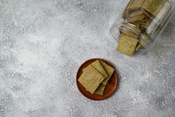 Close up and selective focus of Macha Tea Crackers with cheese in a wooden plate on a white background. The perfect blend for tea time. Grainy noise from the crackers texture