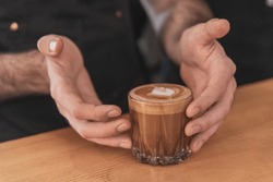Close up barista hands holding  cup of latte art, coffee making barista 