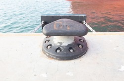 Sturdy metal mooring bollard at pier big lack. single mooring device with coiled ropes keeps ship on dock. Used for large cargo berth use ropes to keep ships from moving.