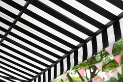 black and white striped awning with green garden. 