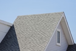Roof shingles with garret house on top of the resident. dark asphalt tiles on the roof background.