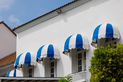 blue and white striped curve awning above the window at balconay of house. Sunshade for store.