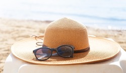 Straw hat and sunglasses on the beach. Beach holiday concept. 