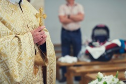 Beautiful golden cross in male hands of priest wearing gold robe on ceremony in christian cathedral church, holy sacramental event
