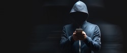holds the phone on a dark background. hacker concept