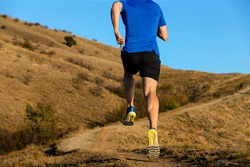 back man runner running mountain trail on background blue sky