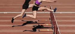 two female athletes running hurdles in athletics competition, hurdling on stadium track, summer sports games