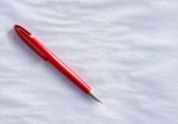 red ballpoint pen or red pen in the photo from above on a white background