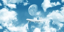 Passenger plane flying in midnight sky among clouds, full moon light in background.
