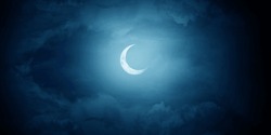 Crescent moon among the clouds in the midnight sky.
