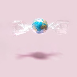 World Earth day concept. Globe in foil on pastel light pink background. Minimalistic environment composition. Creative candy world composition. Beauty of the planet idea.