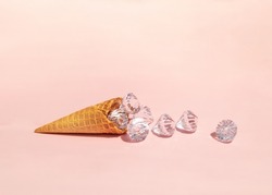 Diamonds in ice cream cone on light pastel pink background. Creative food concept. Minimalistic rich flavor composition. Sunny summer idea.
