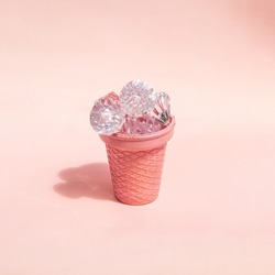 Diamonds in ice cream cone cup on light pastel pink background. Creative food concept. Minimalistic rich flavor composition. Sunny summer idea.