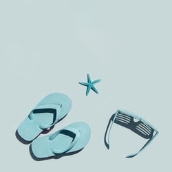Monochromatic beach concept. Sunglasses, flip flops and starfishes on pastel blue background. Creative summer concept. Minimalistic holiday composition with copy space. Holiday flat lay.