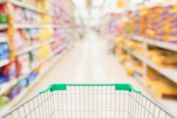 Shopping cart with abstract blur supermarket discount store aisle and pet food product shelves interior defocused background