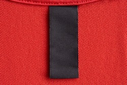 Blank black laundry care clothes label on red fabric texture background