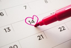 Female Hand with pen mark heart shape on calendar date at 14th valentine day