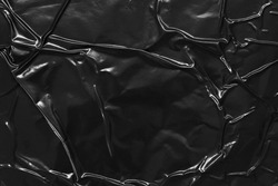 black crumpled and creased plastic poster texture background