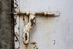 A rusted big latch of a iron white painted door. Rusted kadi. Close up of metallic door latches, Door bolt. Old bolt with rust on in Asian style. Old and rusted door bolts. Darvaje ki kundi.