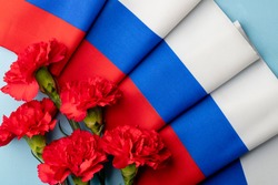 Red carnation flowers on the background of the flag of Russia. February 23 Defender of the Fatherland Day. 22 August Day of the State Flag of the Russian Federation. June 12 is the Independence Day.