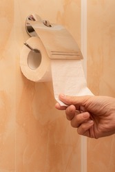 man's hand tears off a piece of toilet paper in the toilet. High quality photo