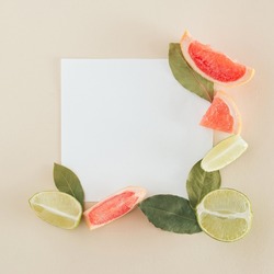 Minimal citrus frame with leaves on a sand colour background. Creative copy space with paper note. Flat lay. Food concept layout.
