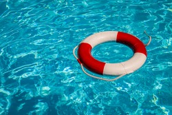 A close up shot of a life guards red and white rescue ring buoy floating in a pool.