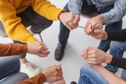 Close up people sit in circle holding hands participating at group therapy session. Receiving sharing psychological support, go through addiction together, help each other overcome dependence concept