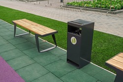 A wooden bench for rest and a garbage bin for waste in a city park