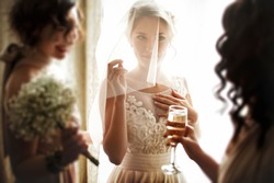 happy stylish gorgeous blonde bride with bridesmaids on the background  hotel room