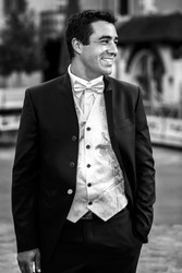 Happy smiling handsome groom in elegant suit closeup b&W