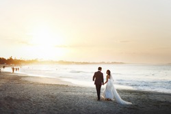 Bride and groom hold each other hands posing on the beach