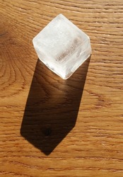 A Single Ice Cube on a Wooden Surface