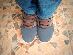 Foots wearing casual canvas shoes and blue jeans on colorful tile foor