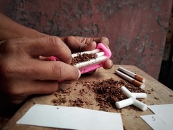 Hands with han tool. Manual working of making cigarette. With tobacco, cigarette paper and filters