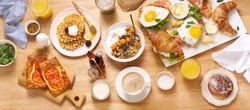Top view image of brunch menu on wooden table. Healthy sunday breakfast with croissants, waffles, granola and sandwiches. Flatlay with tasty food