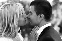 B&W beautiful elegant  blonde bride kissing handsome brunette groom close-up